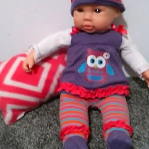 A baby doll and a pink pillow that is homemade